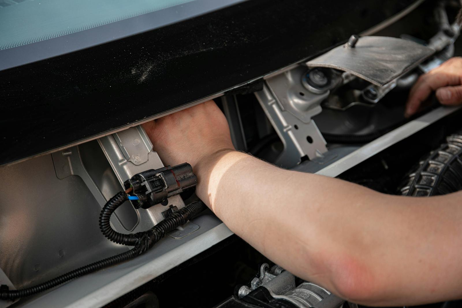 Close-up of mechanic hands repairing car electrical system, showcasing skill and precision.